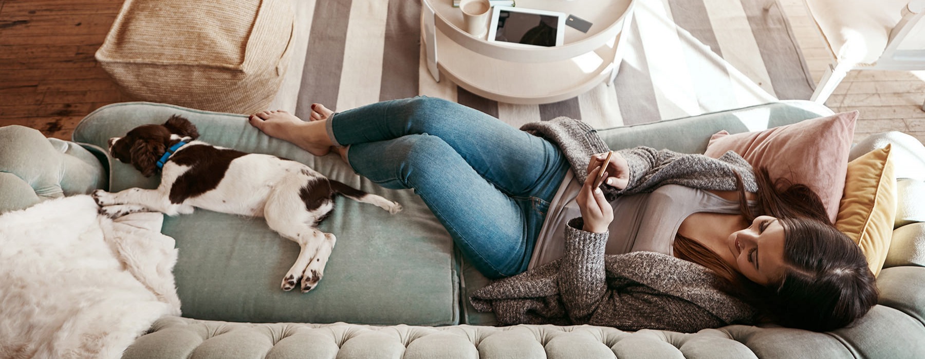 lifestyle image of a woman laying on a couch beside her pet